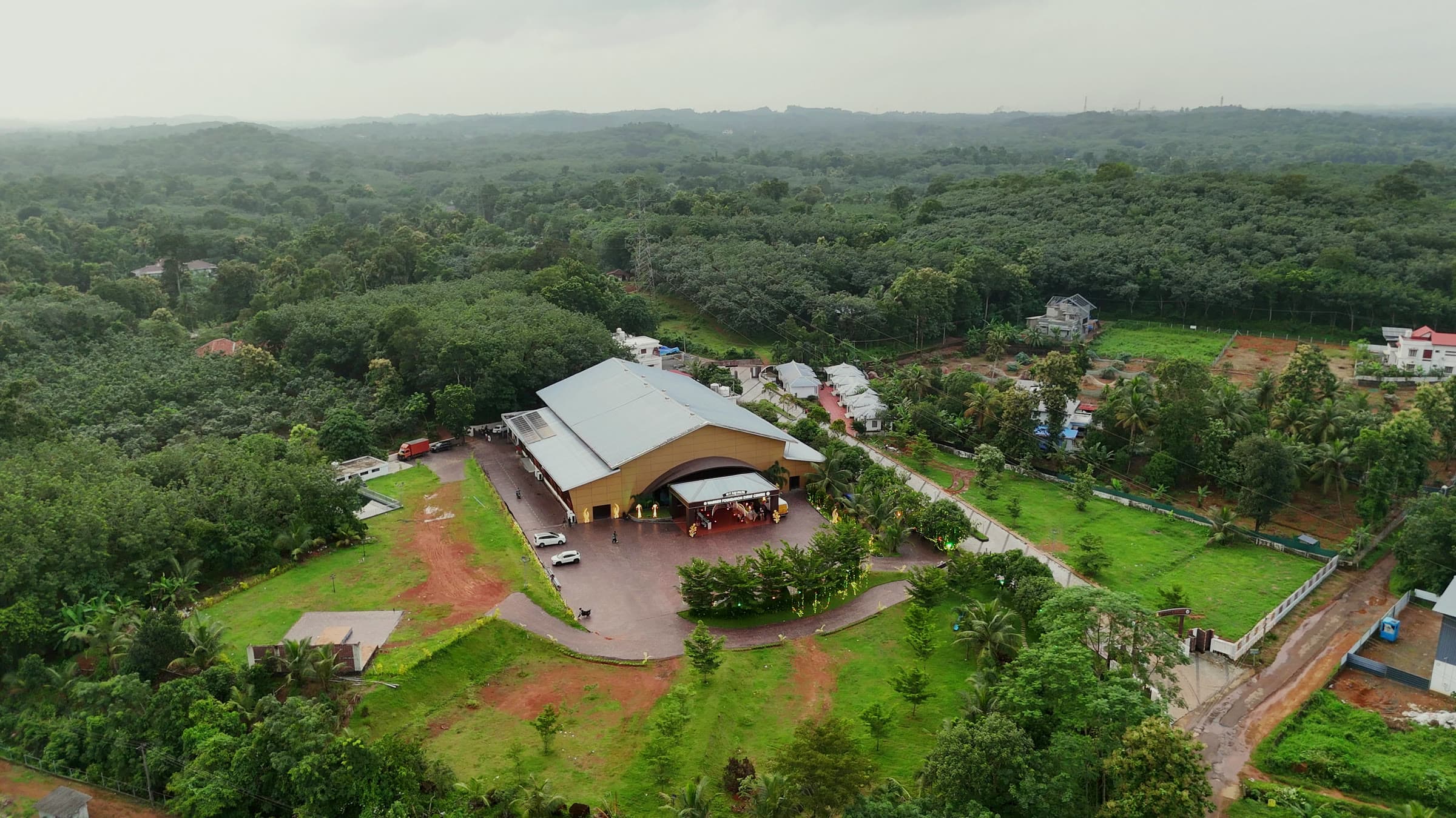 The venue and its grounds seen from the air, wooded hills beyond