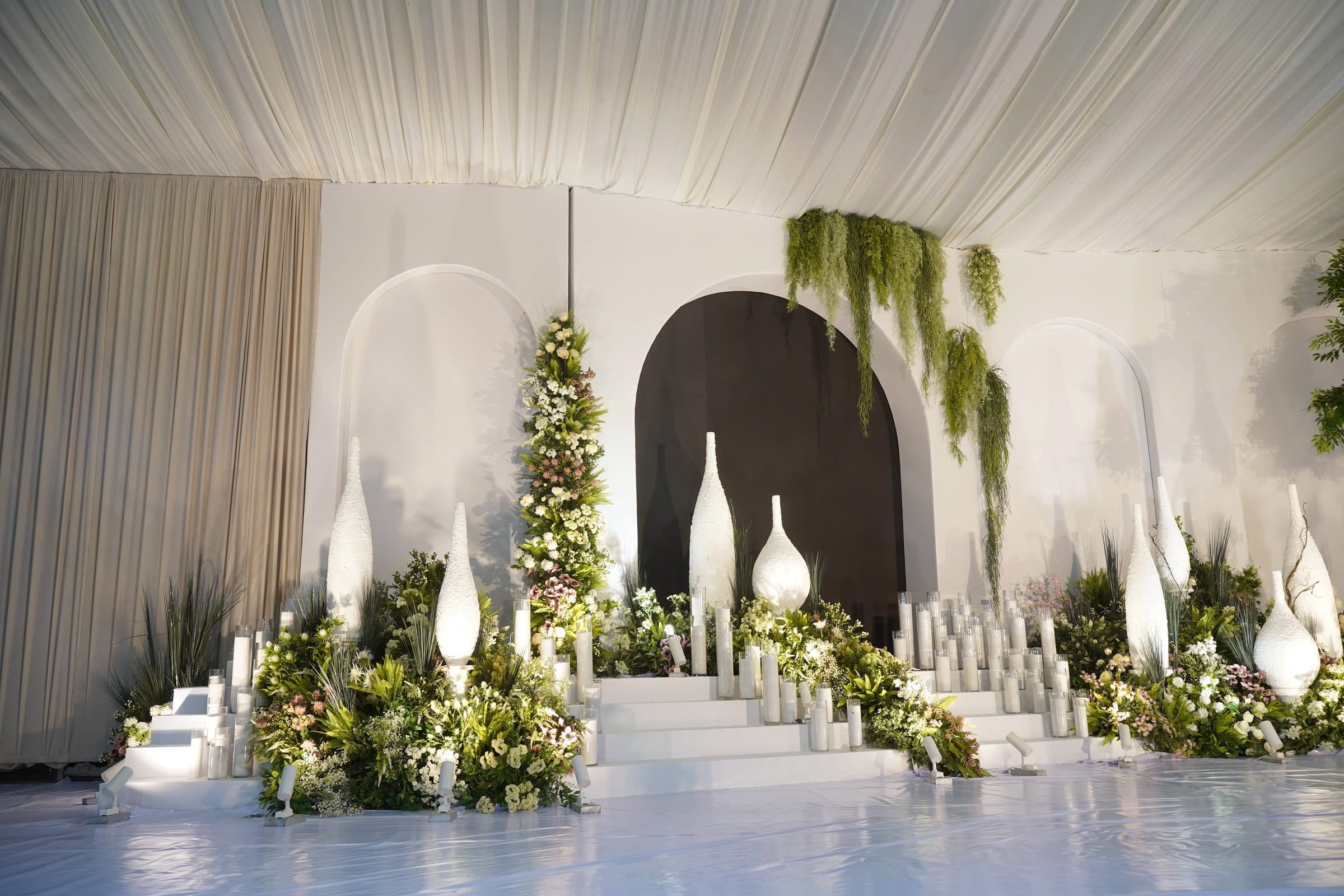 The stage arranged with candles, florals and a dark arched backdrop