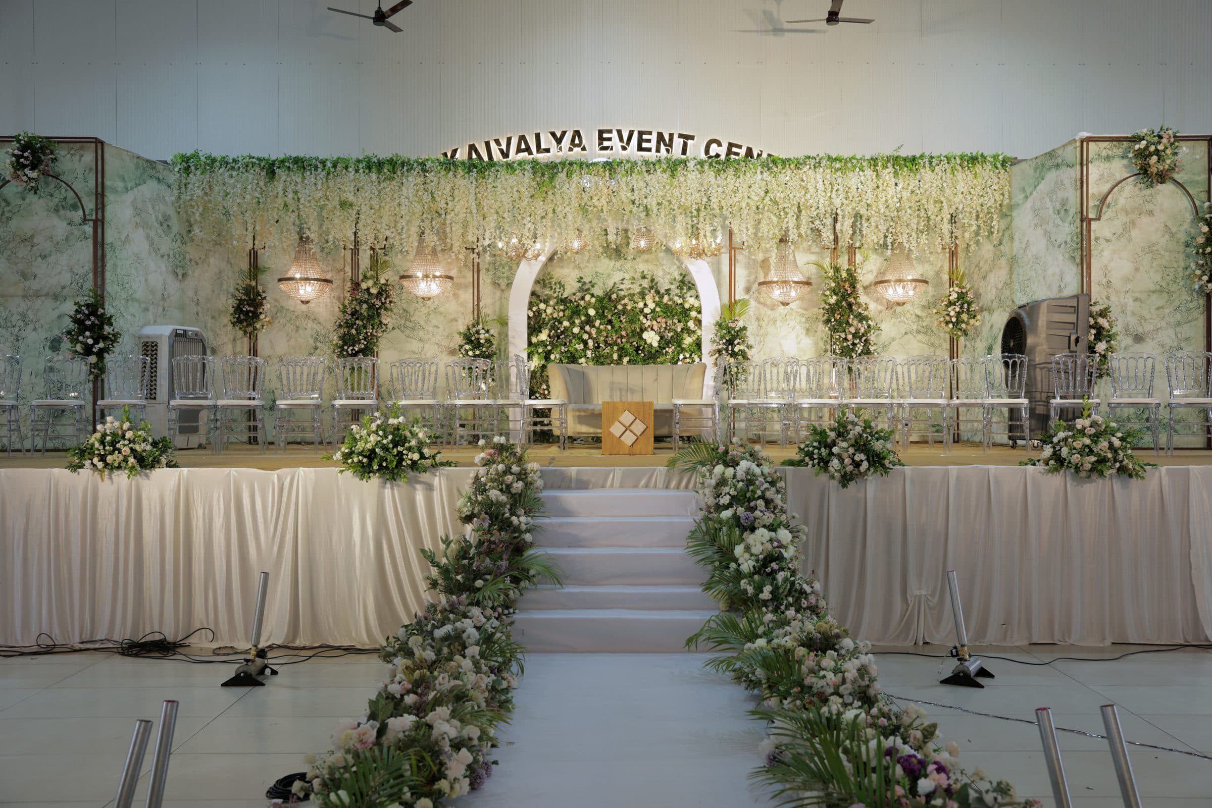 A floral stage backdrop with a garlanded arch and flower-lined steps